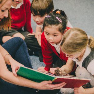 Teacher reading to a group of engaged young students