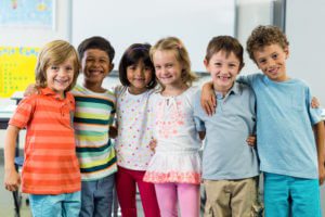Portrait of happy schoolchildren standing in classroom
