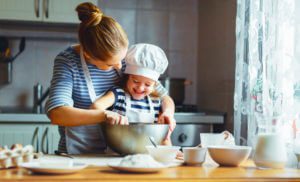 happy family in the kitchen. mother and child daughter preparing the dough, bake cookies