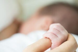 Soft focus and blurry of baby hands touch mother hand while breastfeeding mom
